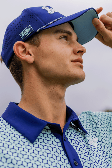 STUD - PREMIUM LIFESTYLE COLLECTION 2026 - BOOYAA GOLF SHIRT, light blue, three-quarter portrait with hand on cap